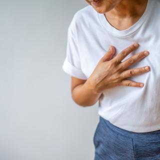 A person experiencing heartburn clutches their chest